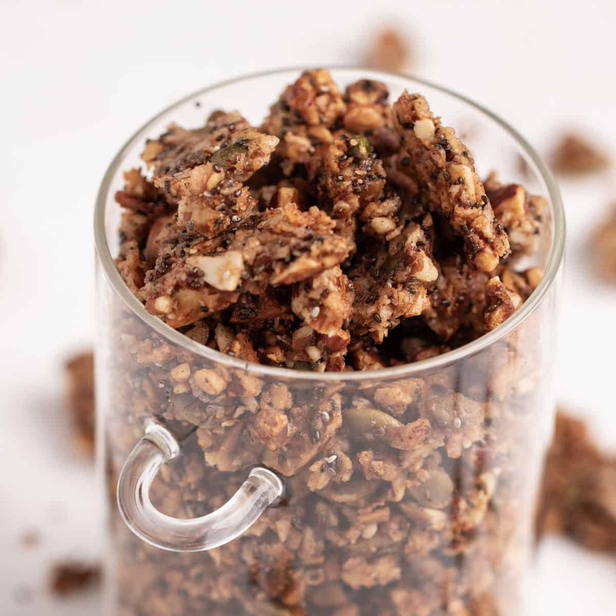 Granola clusters piled high inside of a glass jar.