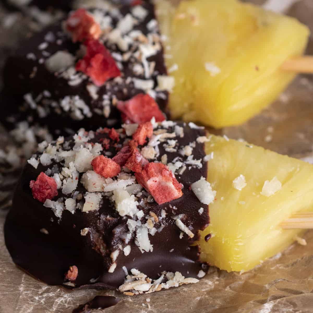 Pineapple dipped in chocolate on a parchment-lined baking tray.