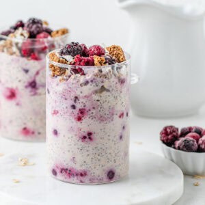 Two glass jars filled with overnight oats and topped with frozen berries and granola.