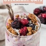 Overnight oats with frozen berries, crunchy granola, and shredded coconut inside of a glass jar.