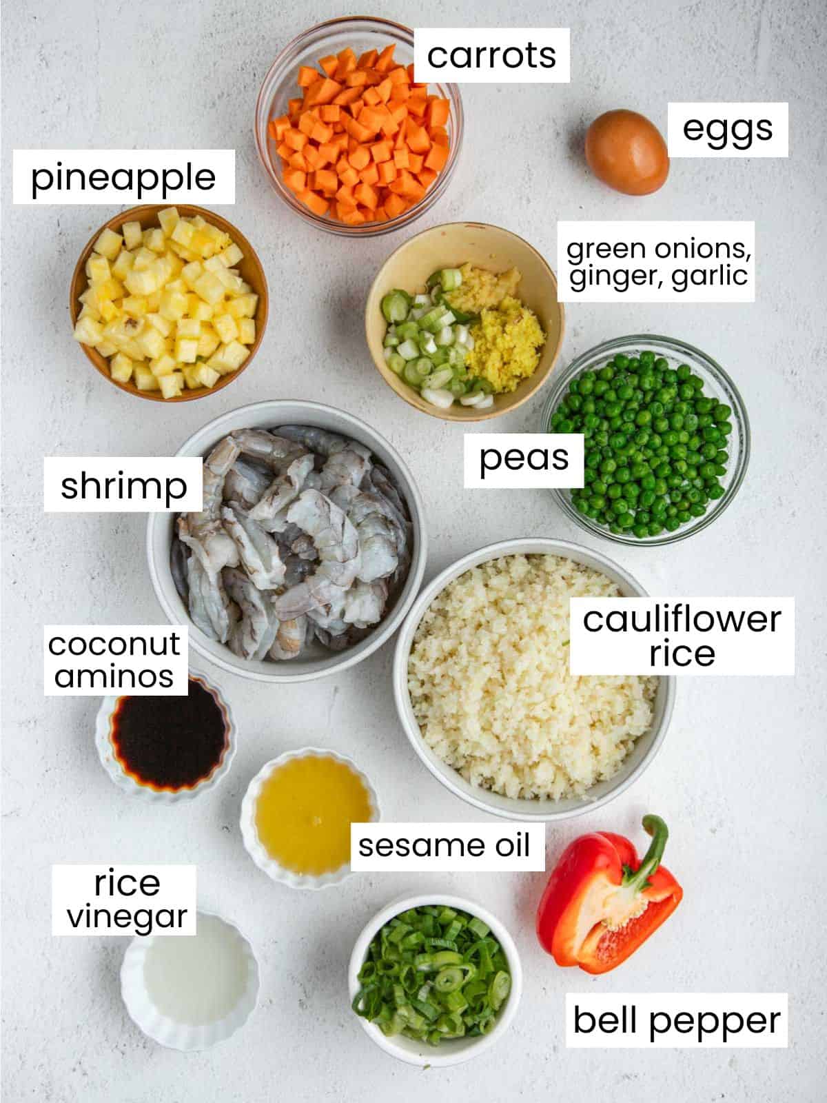List of ingredients: pineapple, carrots, eggs, shrimp, peas, ginger, garlic, green onions, cauliflower rice, coconut aminos, sesame oil, rice vinegar, and bell peppers.