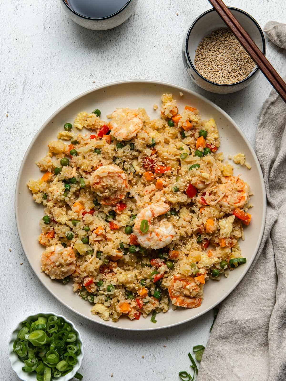 A large round plate filled with cauliflower fried rice with shrimp.