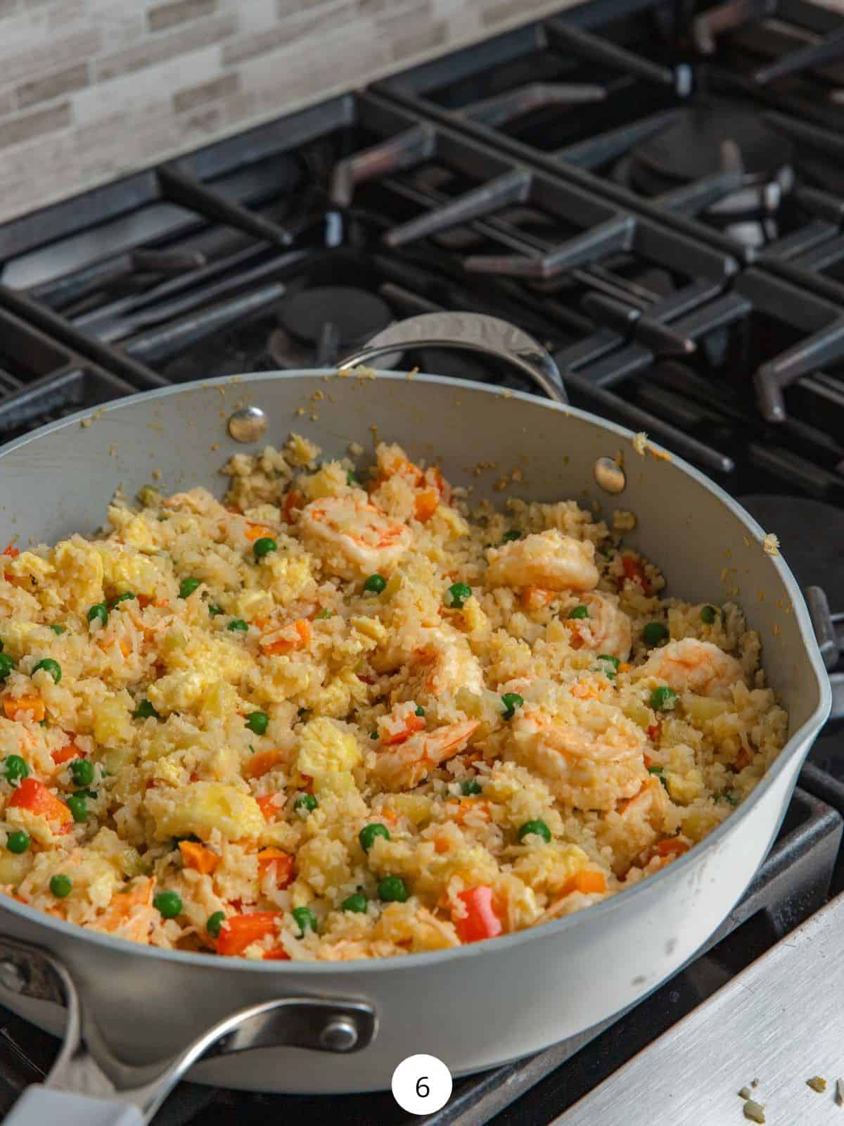 Cooking cauliflower fried rice in a large saute pan.