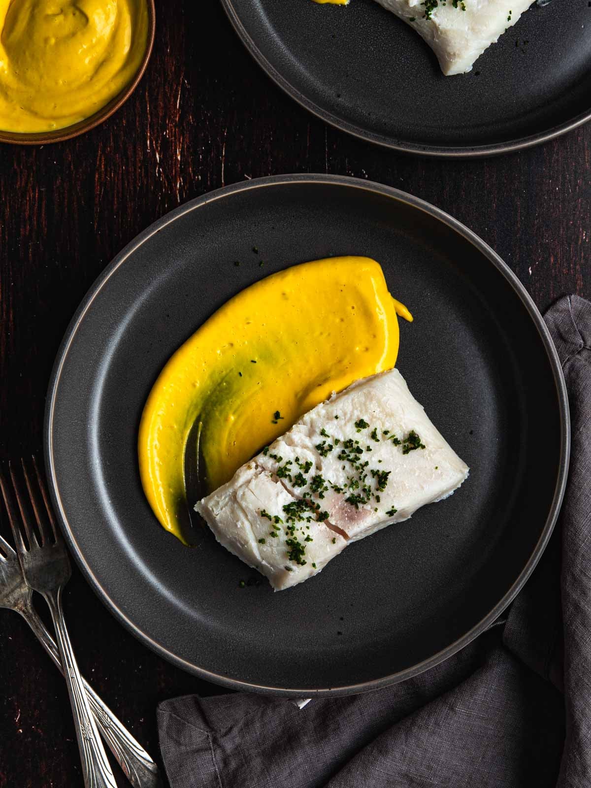 Two plates with sous vide halibut and saffron aioli.