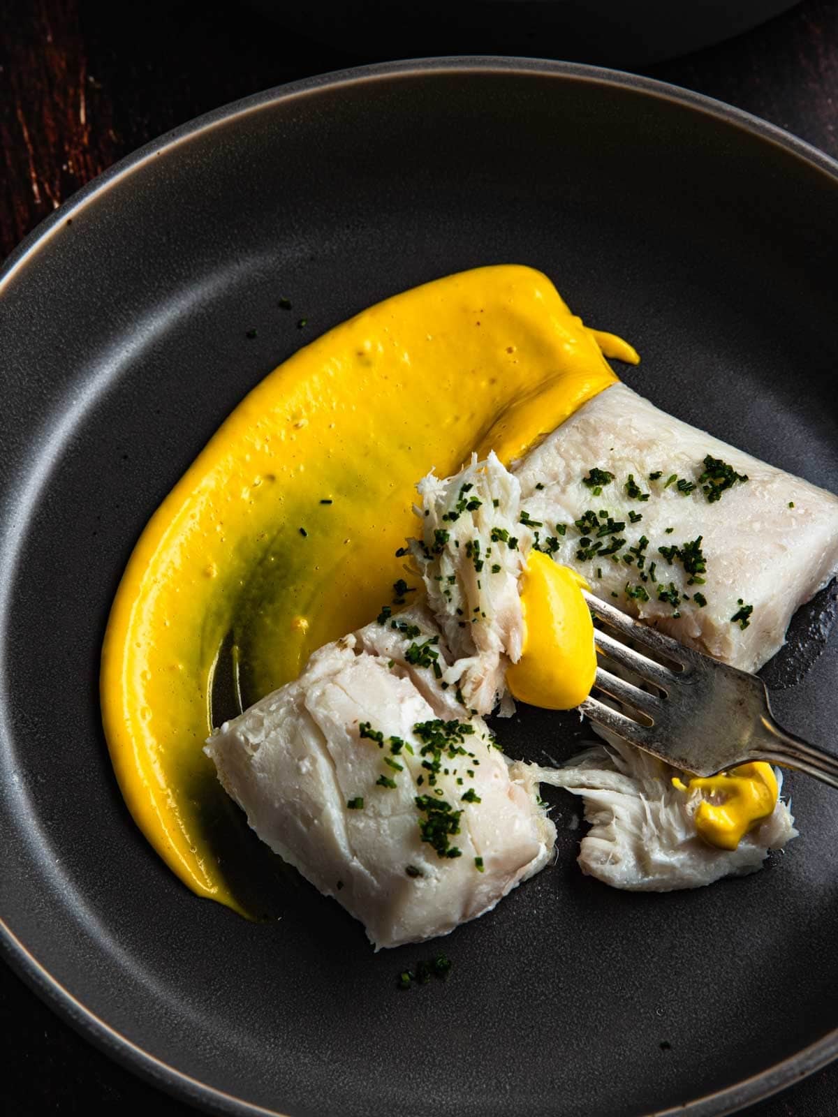 Sous vide halibut with a small bit on a fork with a small amount of saffron aioli.