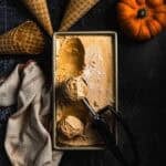 Pumpkin ice cream in a rectangular container with an ice cream scoop.