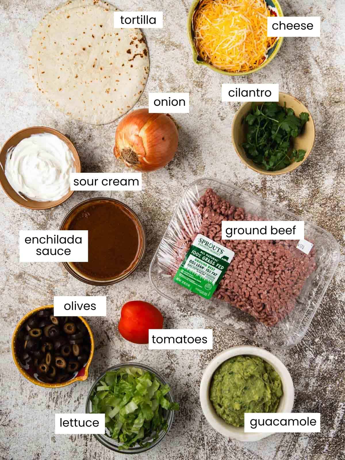 Tortilla, cheese, onion, cilantro, sour cream, enchilada sauce, ground beef, olives, tomato, lettuce, and guacamole.