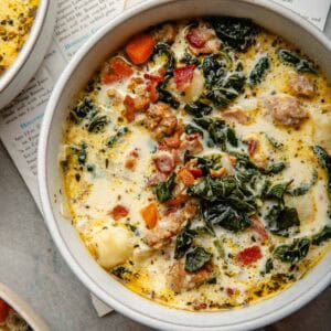 A round bowl filled with a sausage, potato, and kale soup.