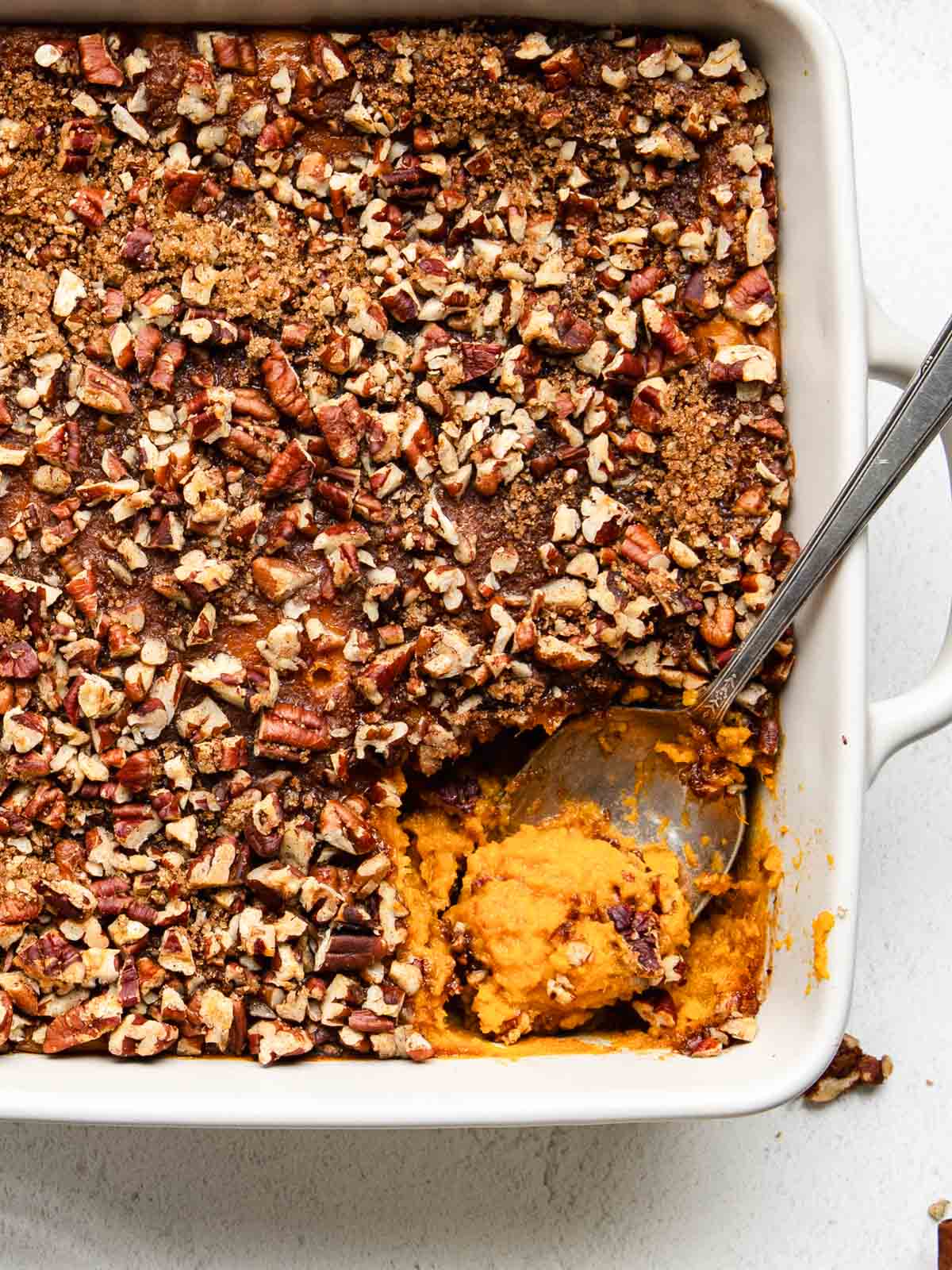 A spoon resting inside of a sweet potato souffle dish.