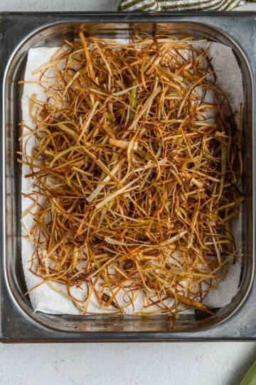 Frizzled leeks on a paper-towel-lined baking pan.