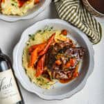Red wine braised short ribs with mashed potatoes and carrots in a light-blue plate.