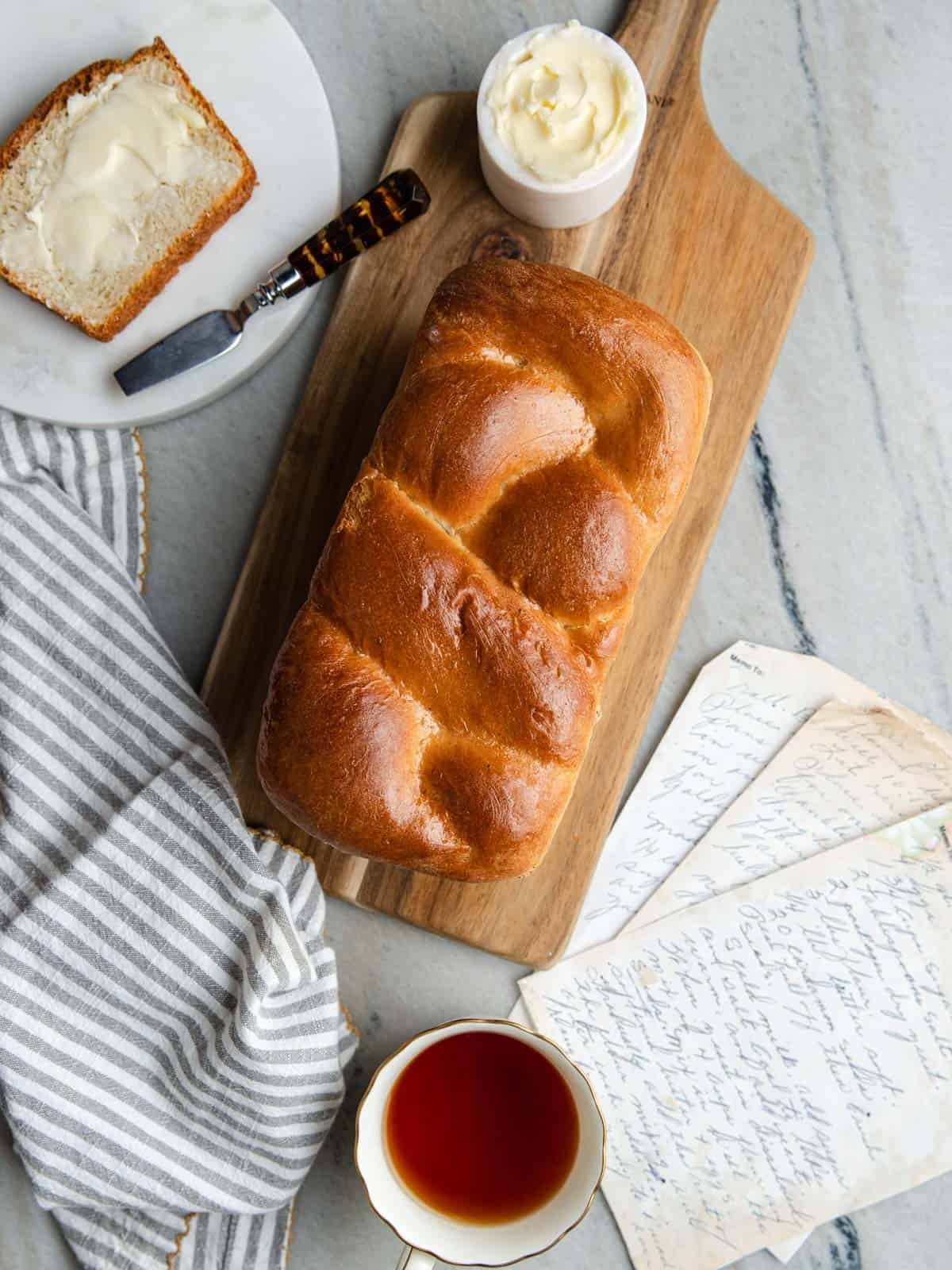 Baked Nisu bread sitting on a wooden cutting board with a slice of bread and butter.