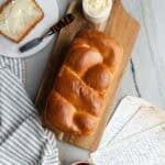 Baked Nisu bread sitting on a wooden cutting board with a slice of bread and butter.
