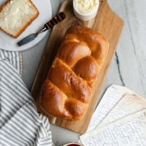 Baked Nisu bread sitting on a wooden cutting board with a slice of bread and butter.