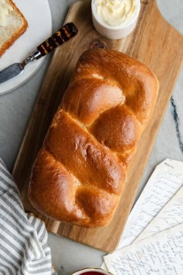 Baked Nisu bread sitting on a wooden cutting board with a slice of bread and butter.