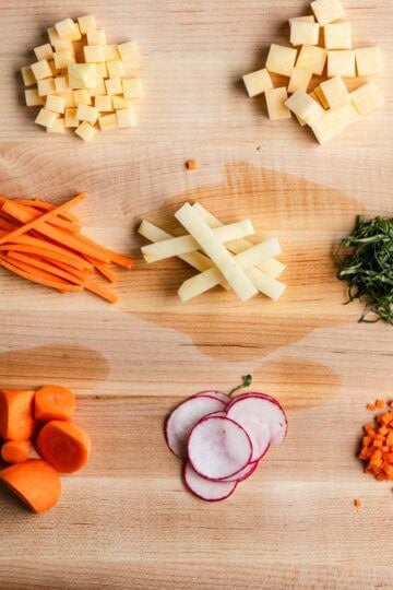 A photo of different knife cuts on a wooden cutting board.
