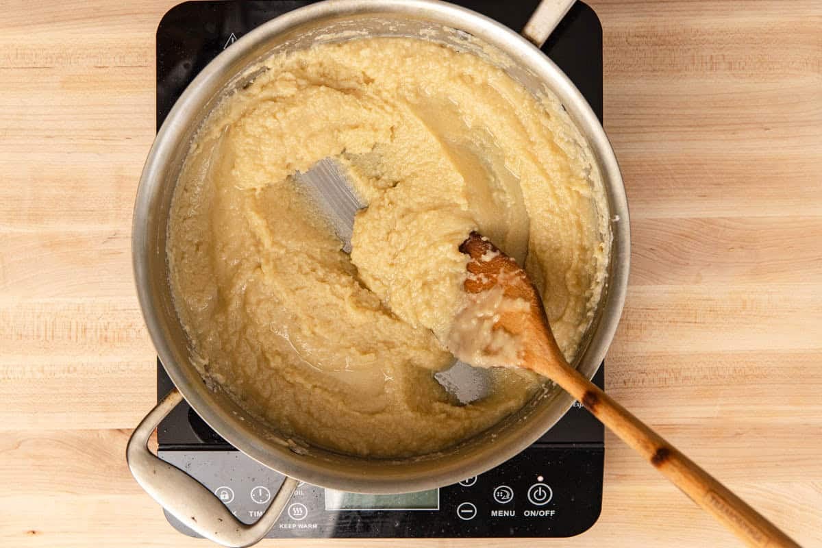 Making a blonde roux in a stainless-steel pan and using a wooden spoon to stir.