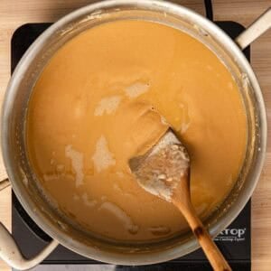 Making a brown roux in a stainless-steel pan and stirring with a wooden spoon.
