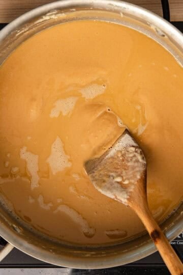Making a brown roux in a stainless-steel pan and stirring with a wooden spoon.
