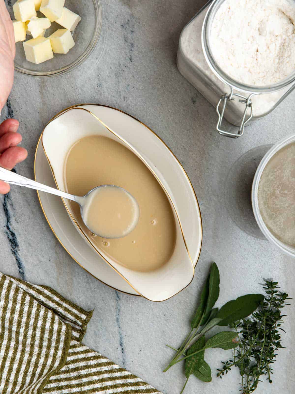 Chicken velouté sauce in served in a gravy boat with a spoon.