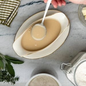 Chicken velouté sauce in served in a gravy boat with a spoon.