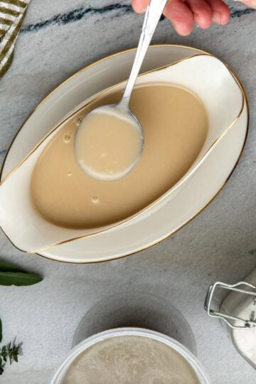 Chicken velouté sauce in served in a gravy boat with a spoon.