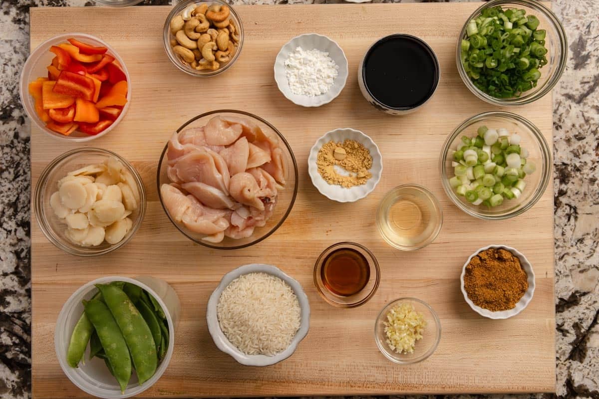 Mise en place ingredients in small glass prep bowls sitting on a large wooden cutting board.