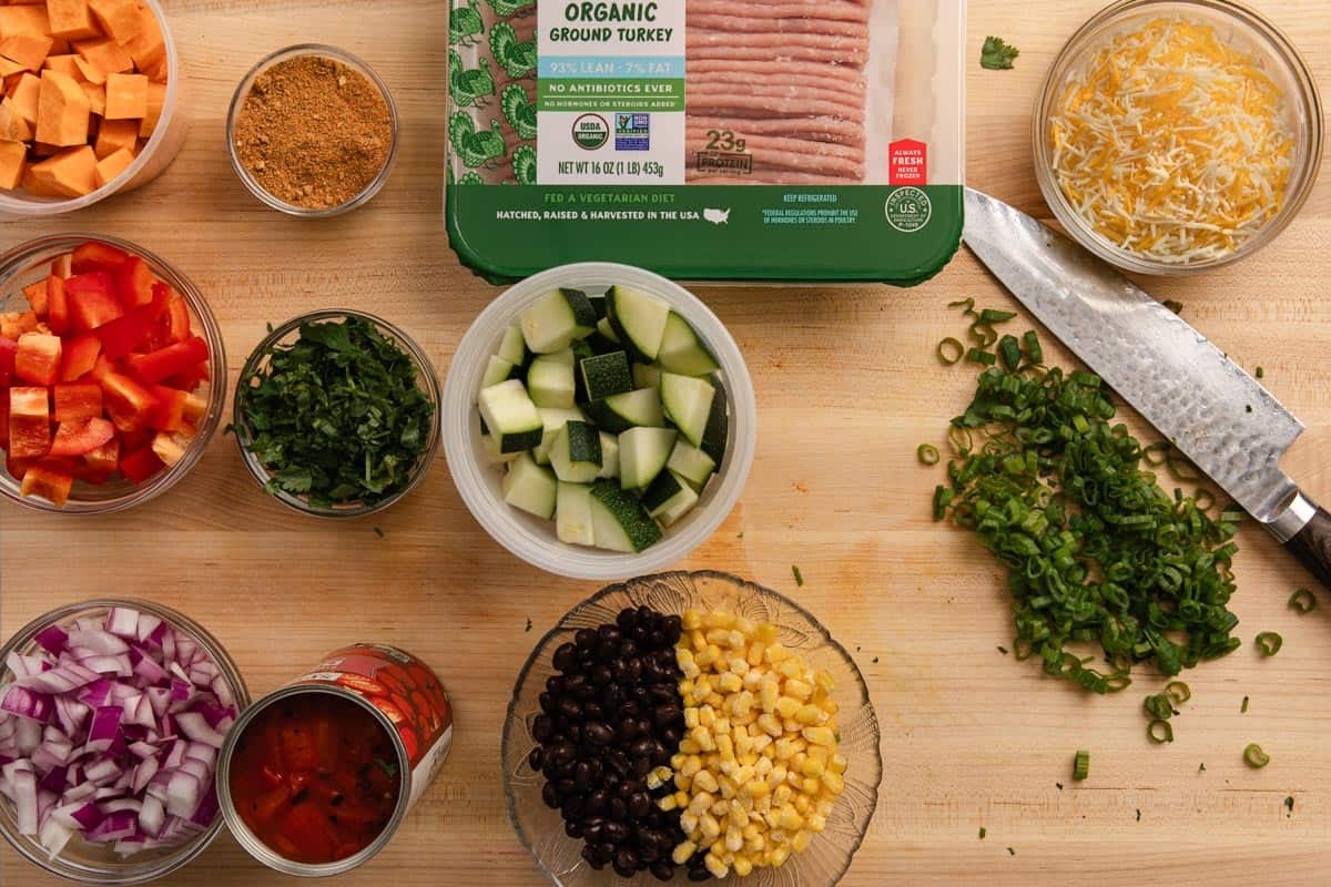 Small glass bowls of mise en place ingredients on a wooden cutting board.