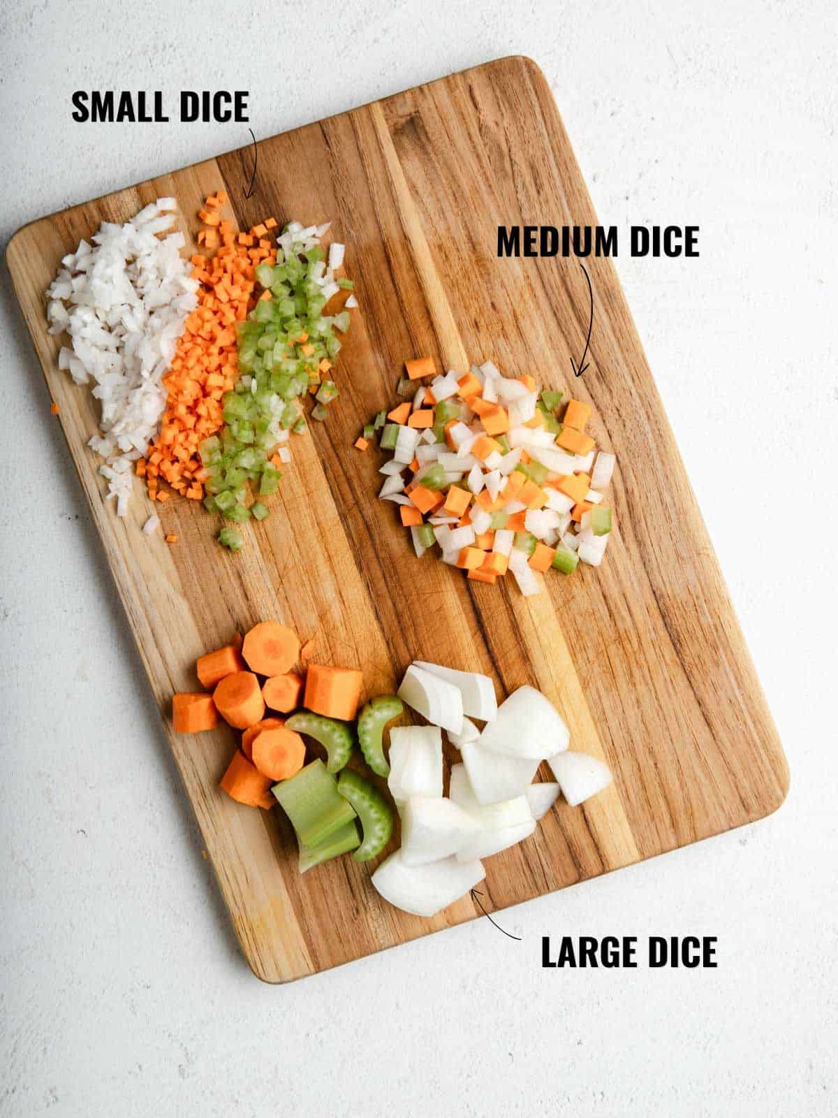 Demonstrating small, medium, and large diced mirepoix on a wooden cutting board.