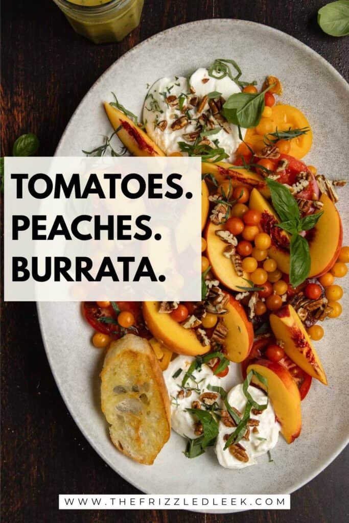 Tomato, peach, burrata salad on an oval serving platter with fresh basil.