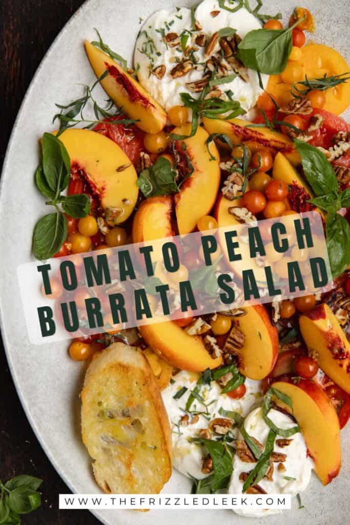 Tomato, peach, burrata salad on an oval serving platter with fresh basil.
