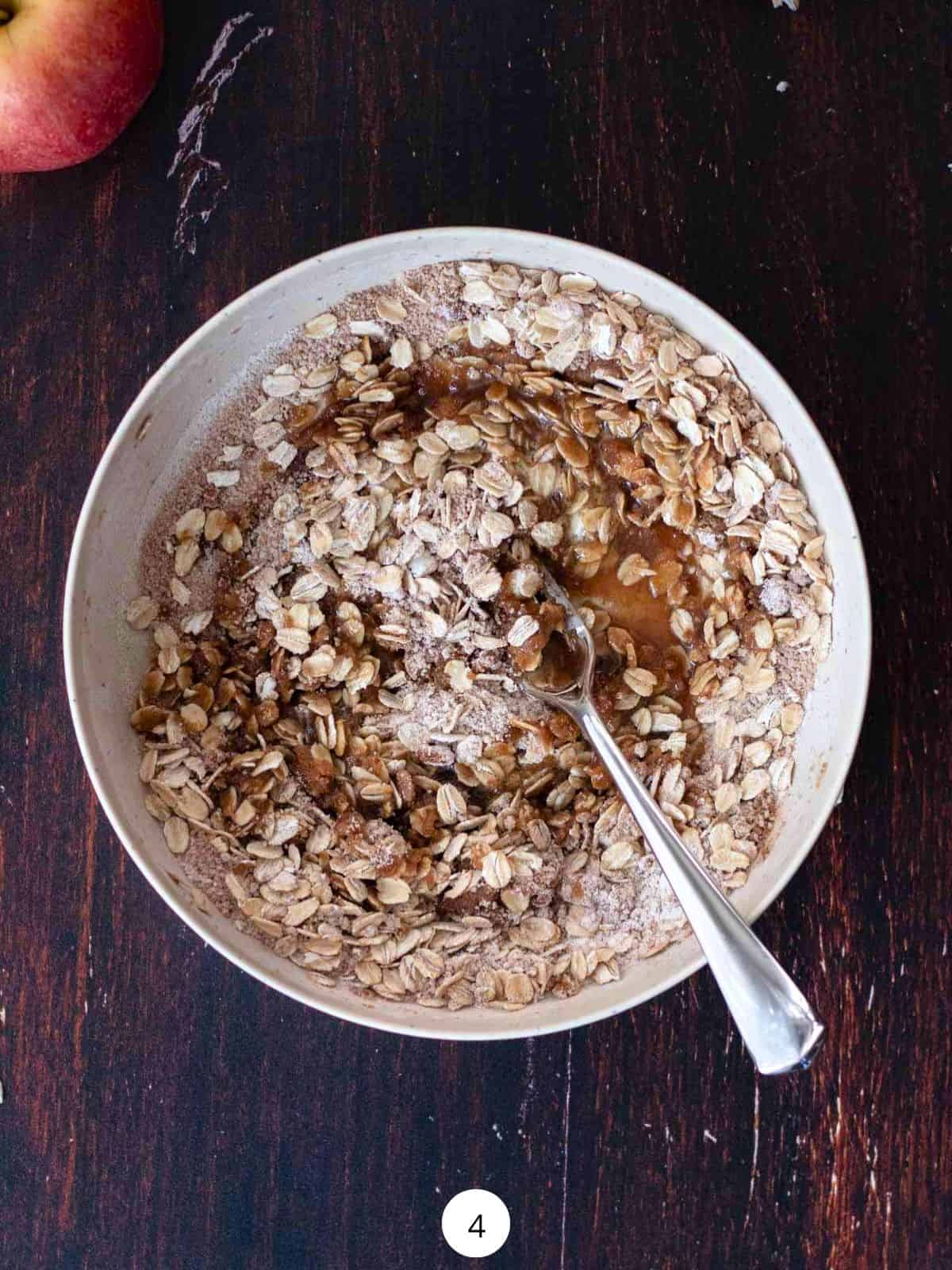 Mixing oatmeal crisp topping together in a round bowl with a fork.