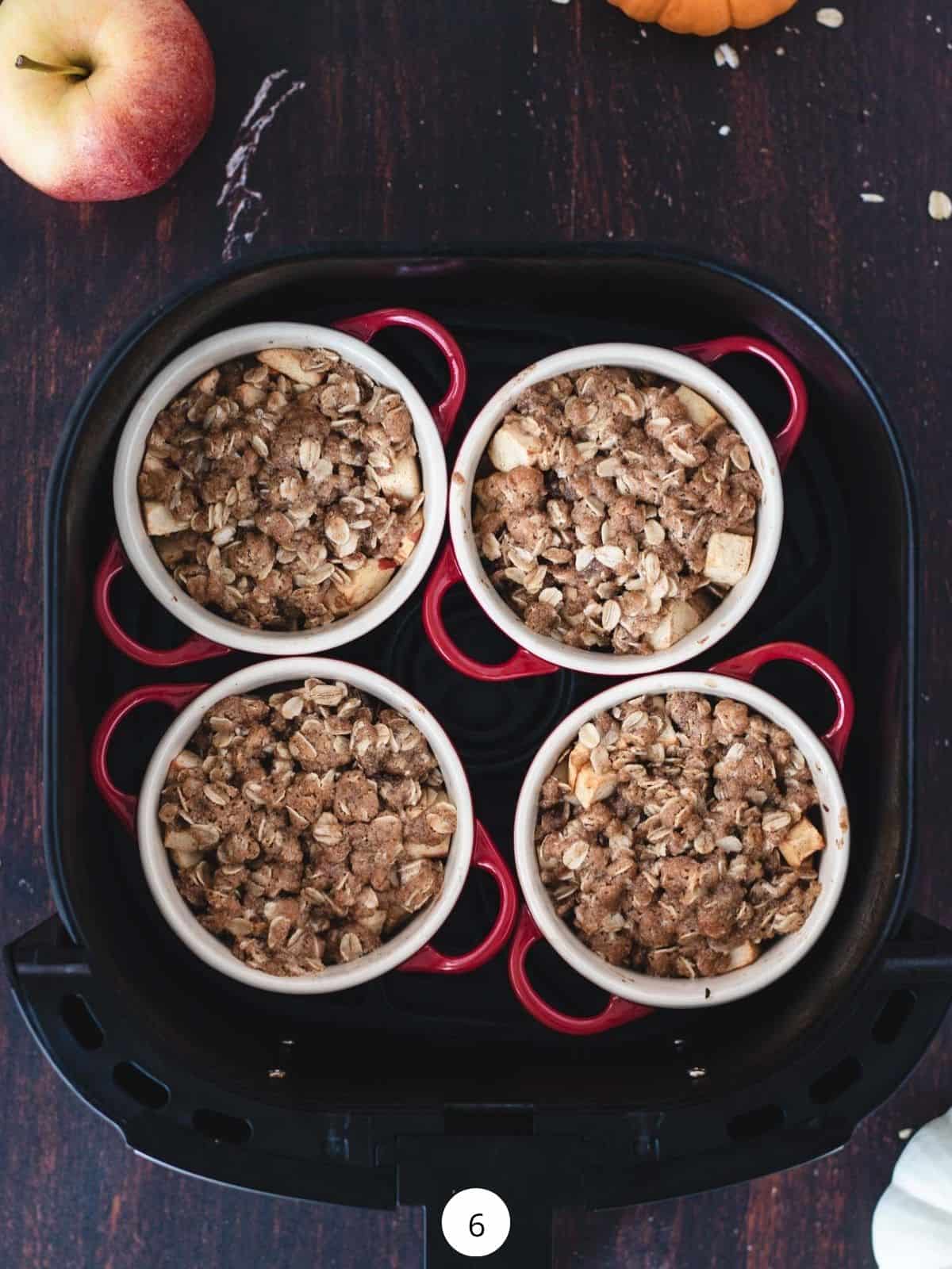 Four individual apple crispy inside of an air fryer basket.
